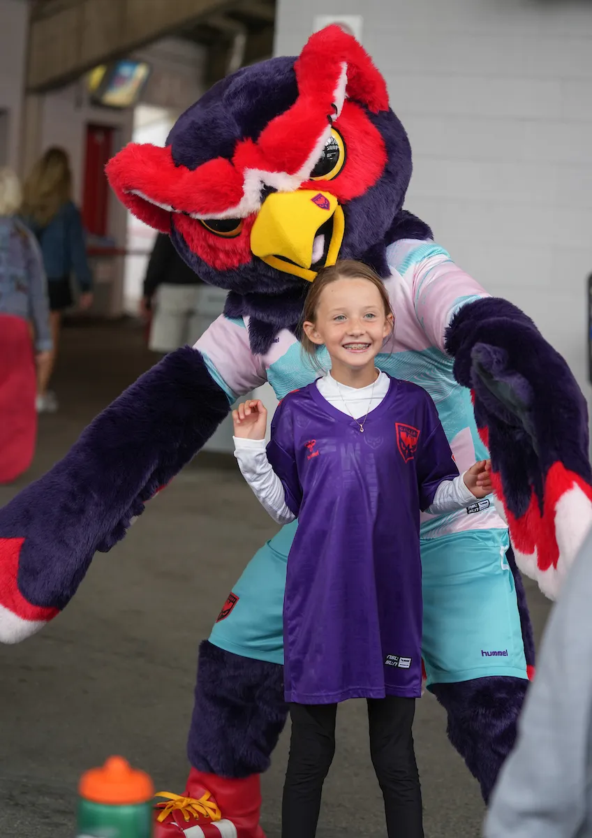 Calgary Wild mascot Echo posing for a photo with a young fan at a match